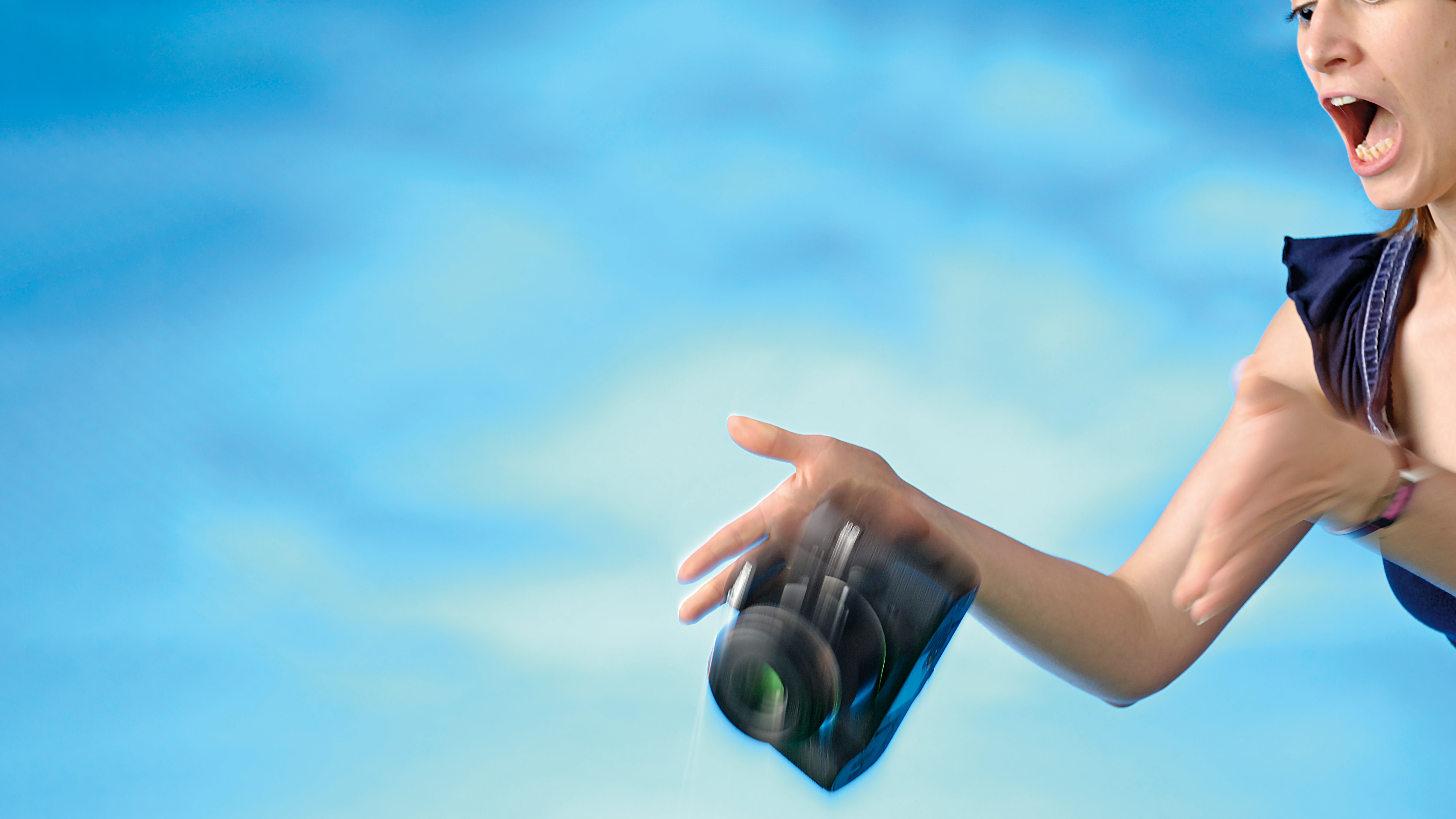 Woman looking horrified as she drops DSLR camera