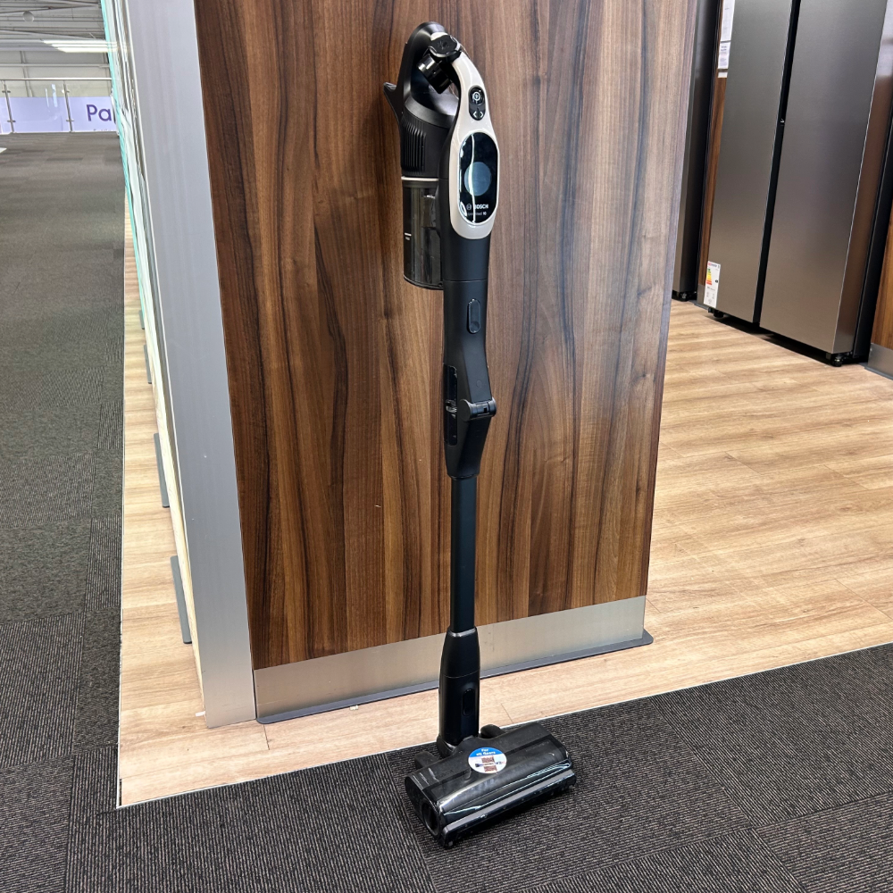 Bosch Cordless Vacuum Cleaner Unlimited 10 standing against a wooden wall, one of the best vacuum cleaners for pet hair
