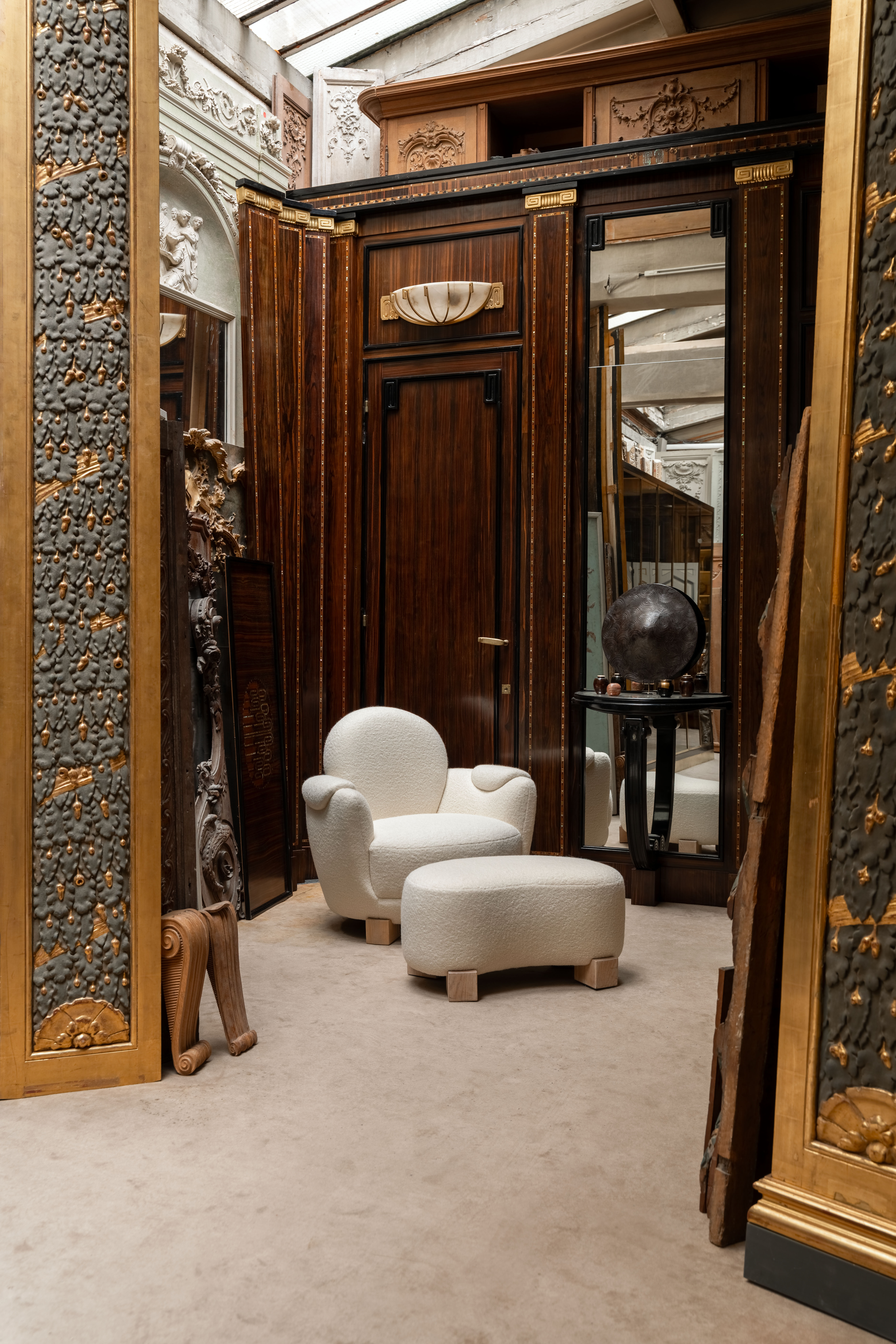 White armchair and footrest in a decorated French interior with mirrors in the background