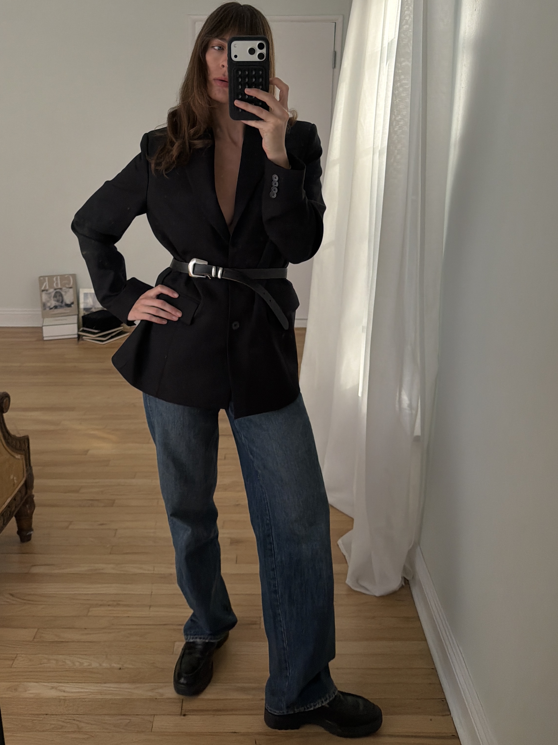 Kathryn Zahorak posing in mirror wearing black blazer, belt, baggy jeans, black boots