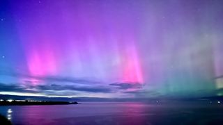 Vibrant pink aurora display from Cullen on the Moray Firth in Scotland looking towards Bow Fiddle Rock.