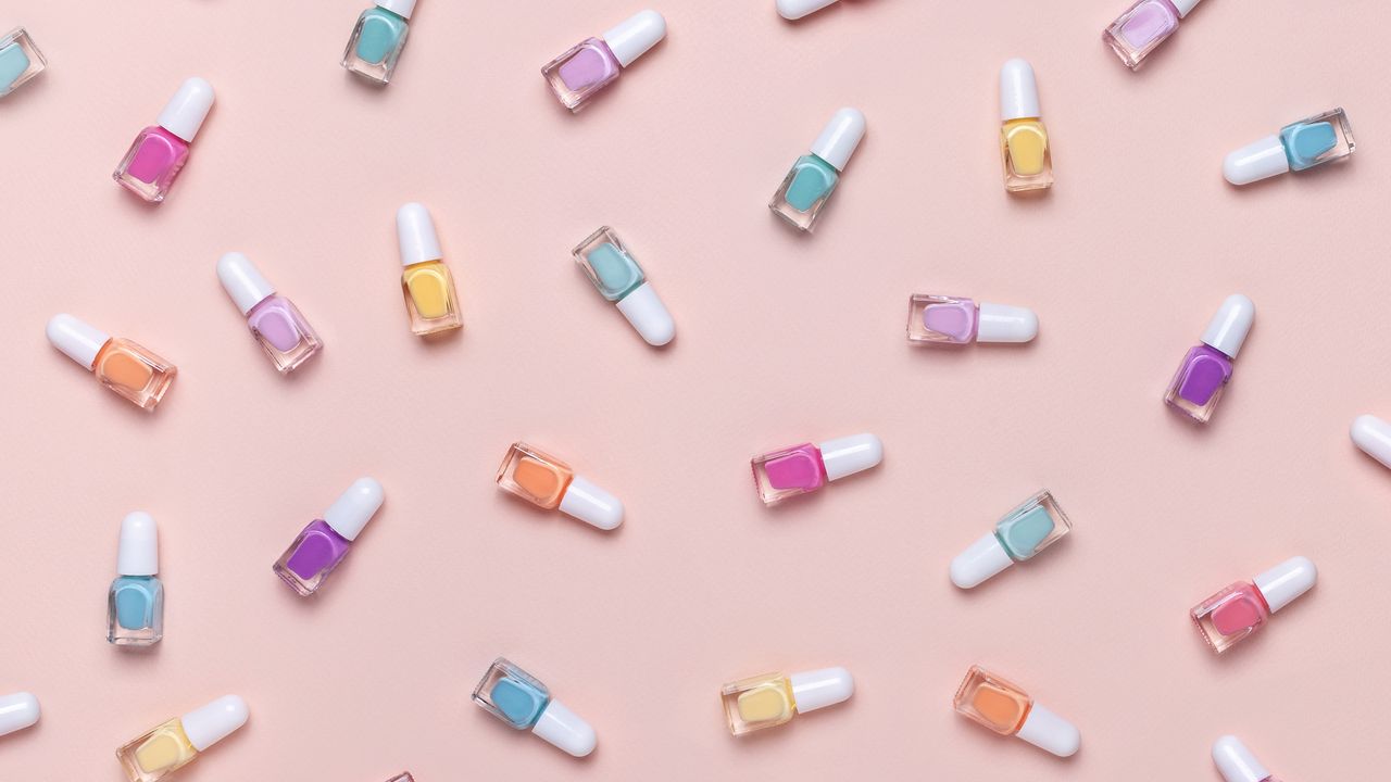 An assortment of pastel-colored nail polish paints on pink background