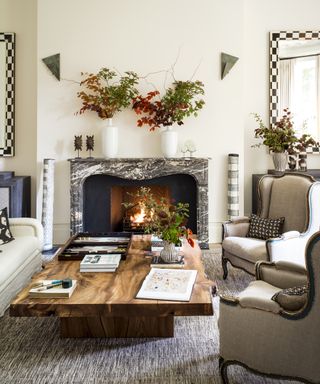 Fall mantel ideas with white walls, grey marble mantel and autumnal leaves in vases