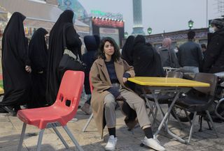 A young woman sitting in front of a mosque in Tehran, Iran, photographed by Ahmad Halabisaz.
