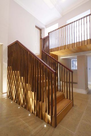 The Portledge Rear Staircase by Witcher Crawford Architects and Designers, neutral stone floor, wood design staircase, white walls, floor spotlights, ground floor entrance with window, upper floor hallway, window with daylight coming through