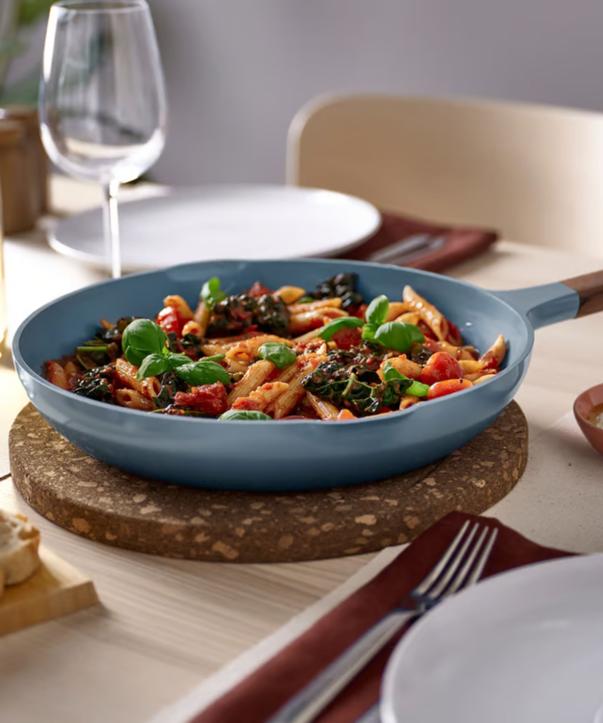 Turquoise frying pan on cork trivet on a wood dining table