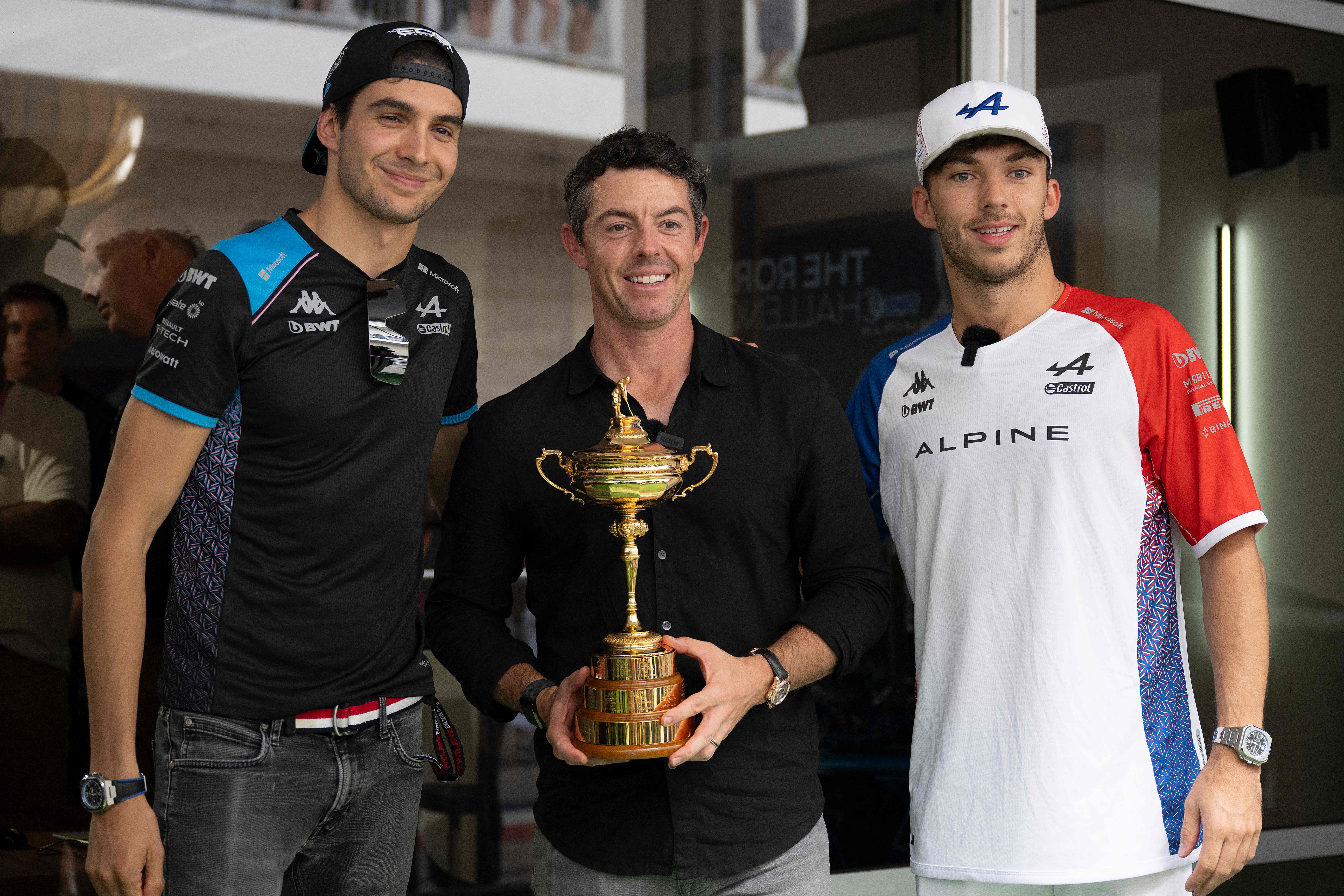 Esetban Ocon, Rory McIlroy and Pierre Gasly pose for a photo, while McIlroy holds the Ryder Cup