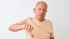 A serious-looking older man gives a thumbs-down.
