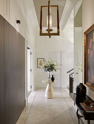 grand hallway/entryway with console table and flowers, large pendant light, marble floor