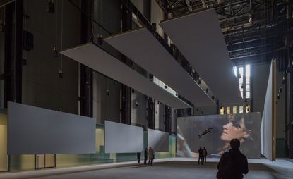Philippe Parreno today unveiled his new installation, Anywhen, for the Tate Modern’s annual site-specific Turbine Hall commissions, sponsored by Hyundai. A large hall with grey rectangular panels on one wall and a large projector screen on the other.