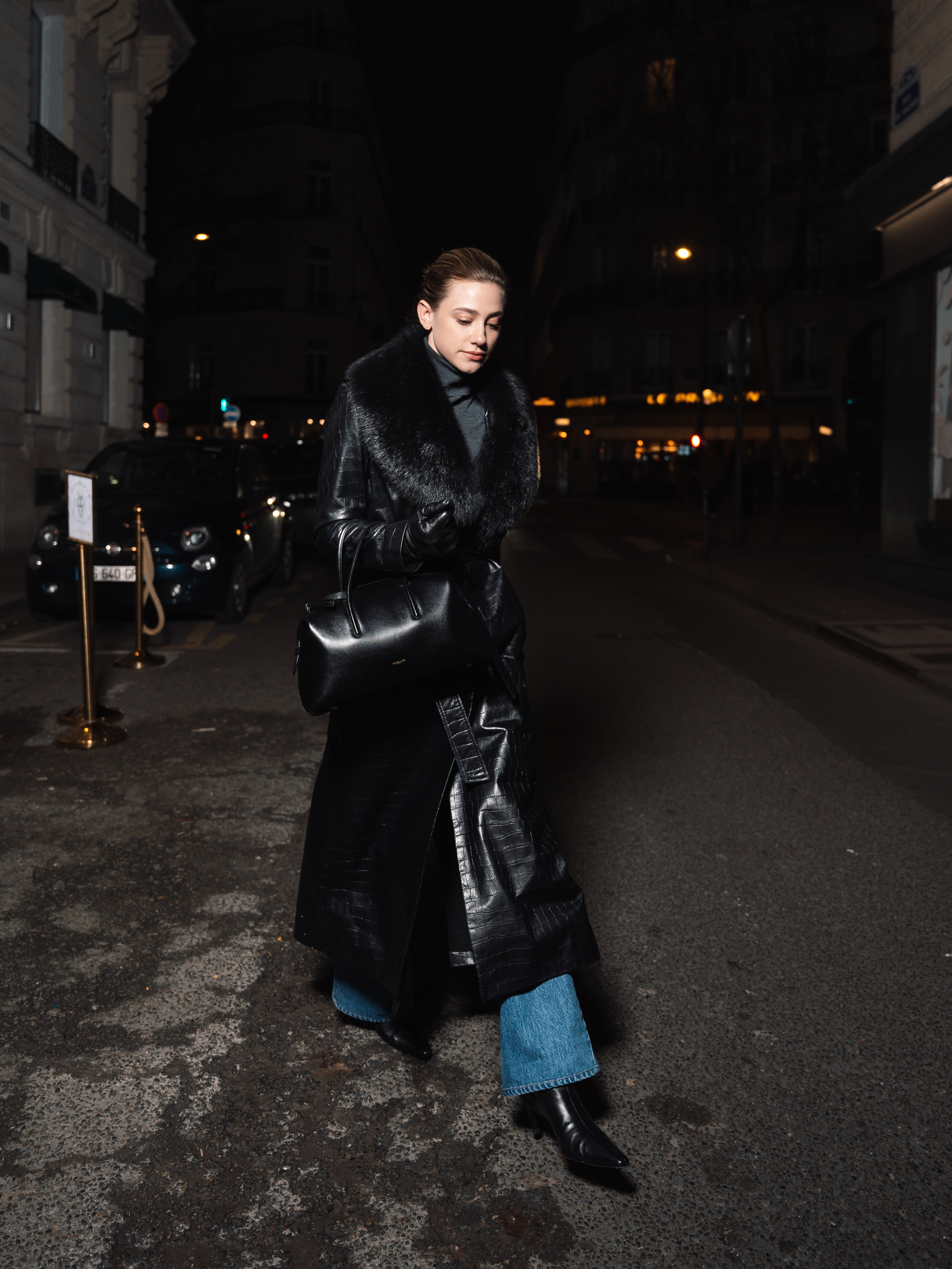 Lili wears the stockholm bag in black with a black coat, blue jeans, and black boots.