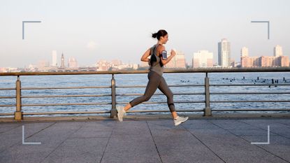 Woman running along the river on a path with workout clothes on and phones listening to music after asking should I run every day