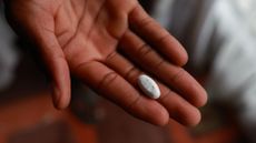 Hand holds a single white pill