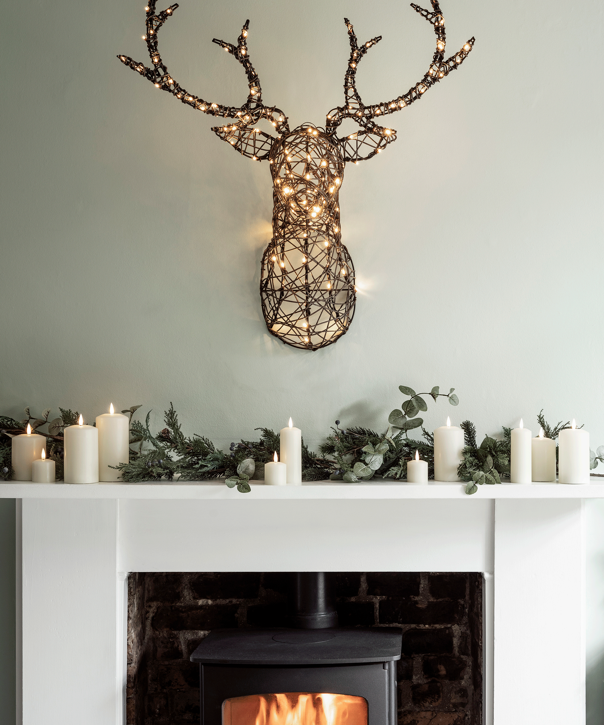 Warm White Rattan Illuminated Christmas Stag's Head above a woodburning stove and white fireplace