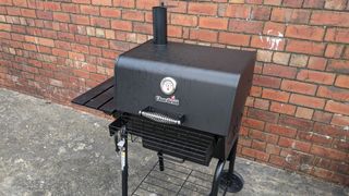 A Char-Broil gas grill placed next to a wall