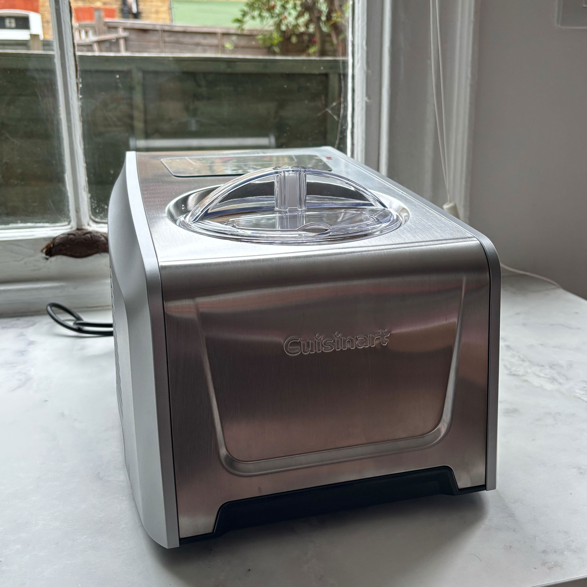 Stainless steel Cuisinart ice cream maker on top of a white kitchen countertop
