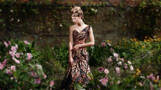 Model wearing a butterfly dress in a flower garden
