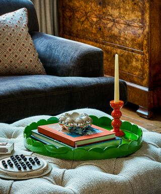 Green lacquer scalloped tray on an ottoman with blue velour sofa and lacquer orange candle holder