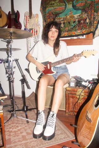 Julia Kugel of the Coathangers playing guitar next to an acoustic drum kit