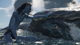 Still from the movie Avatar: The Way of Water (2022). Here we see Jake Sully (a Na'vi with blue skin and long black hair) floating in the ocean next to a giant whale-like creature. He is holding out a hand and petting the giant sea creature.