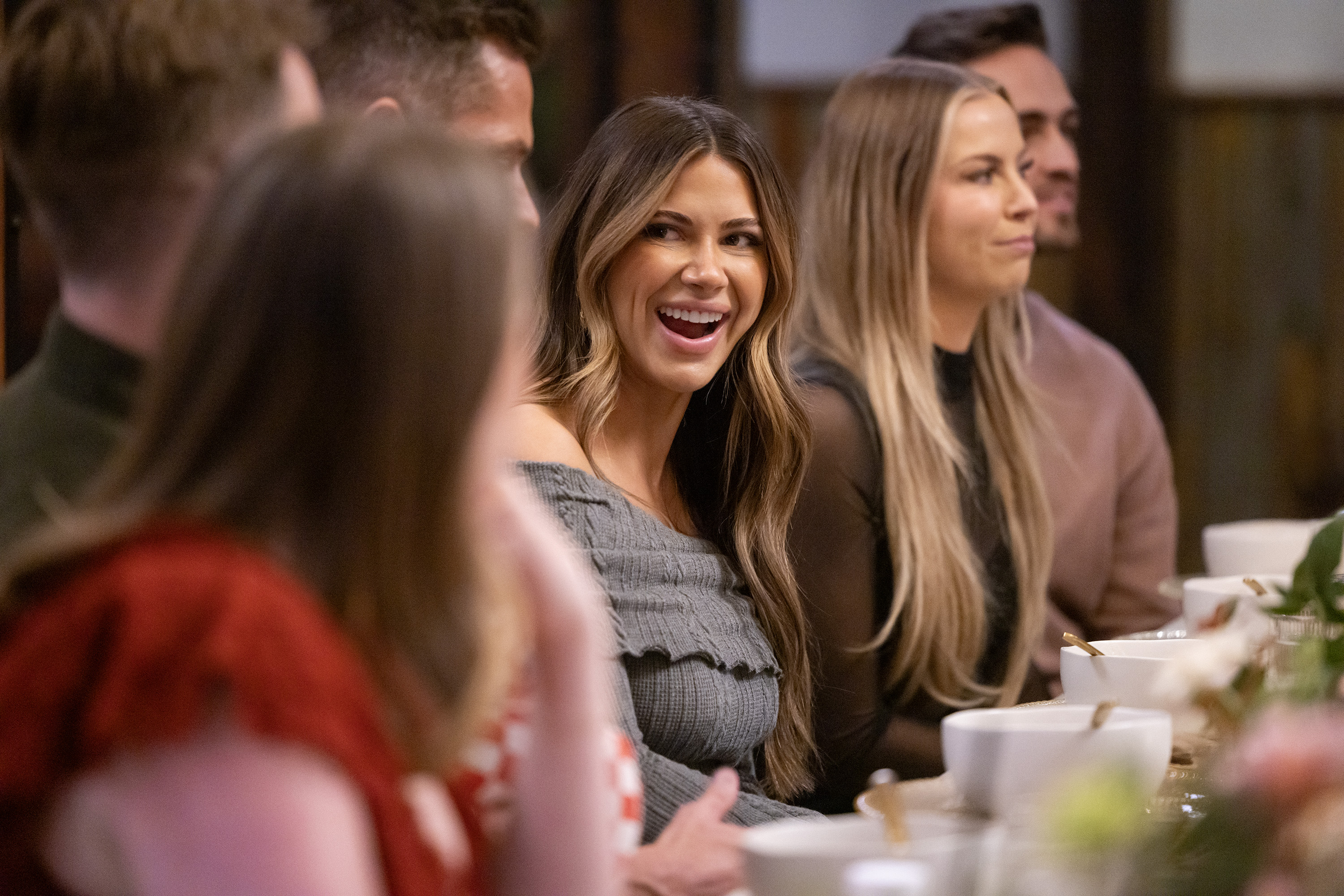 Demi Engemann (center) and Mayci Neeley (center right) sit at a crowded dinner table, in 'The Secret Lives of Mormon Wives.'
