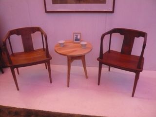 Two wooden armchairs with round backrests, separated by a paler coffee table
