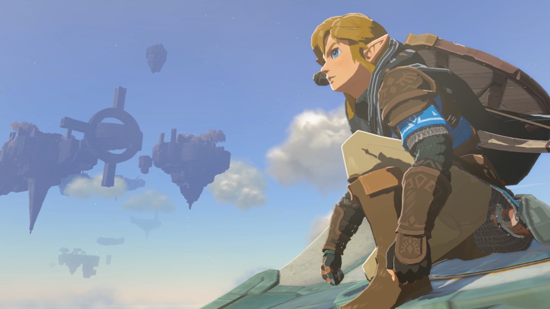 Link crouches, looking out over Hyrule. A sky island can be seen floating in the background