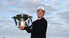 Tom Kim smiles and poses with the Genesis Scottish Open trophy following his win in 2026