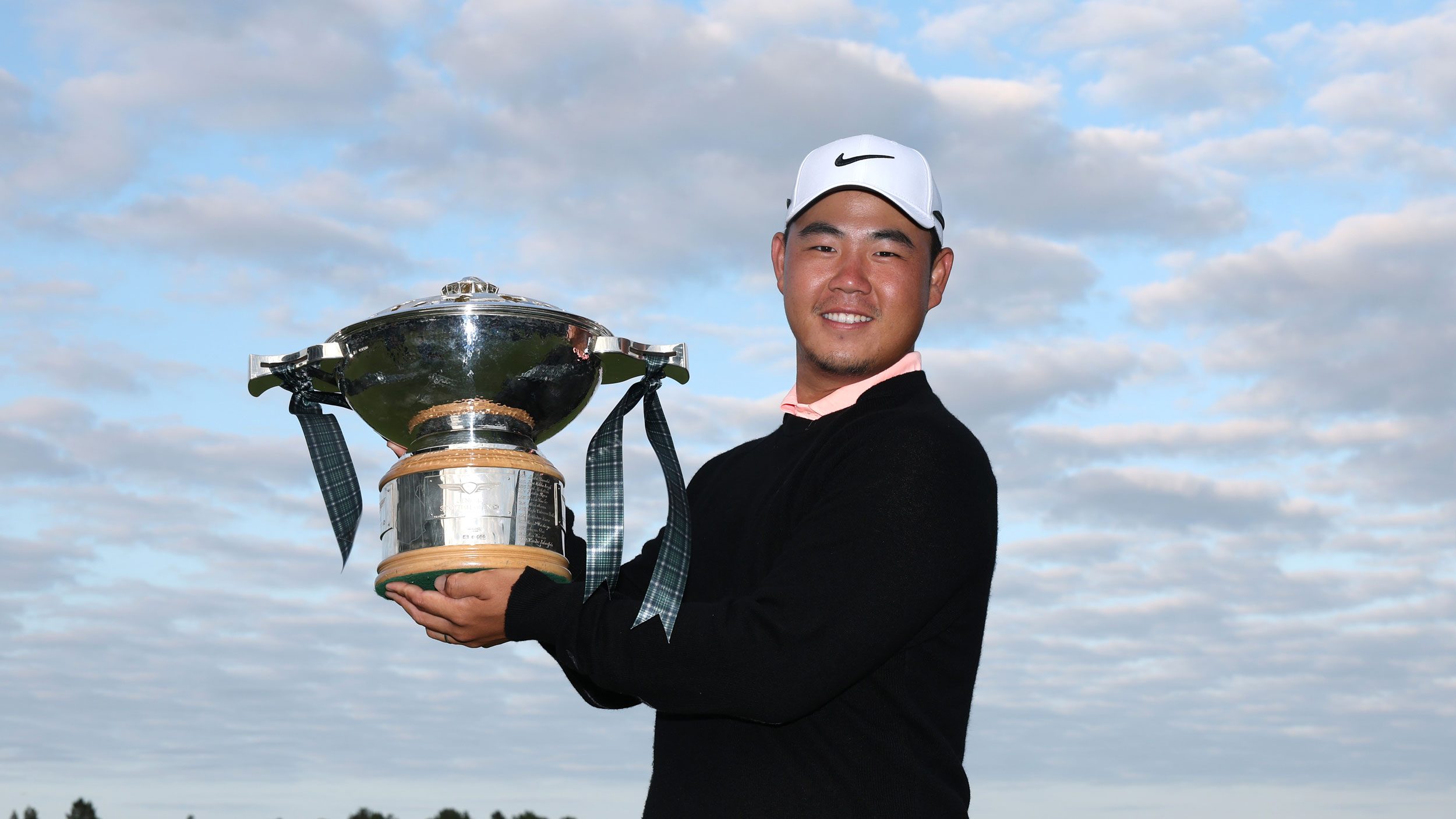Tom Kim smiles and poses with the Genesis Scottish Open trophy following his win in 2026