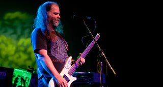 Joe Preston plays a white headless bass onstage with Thrones