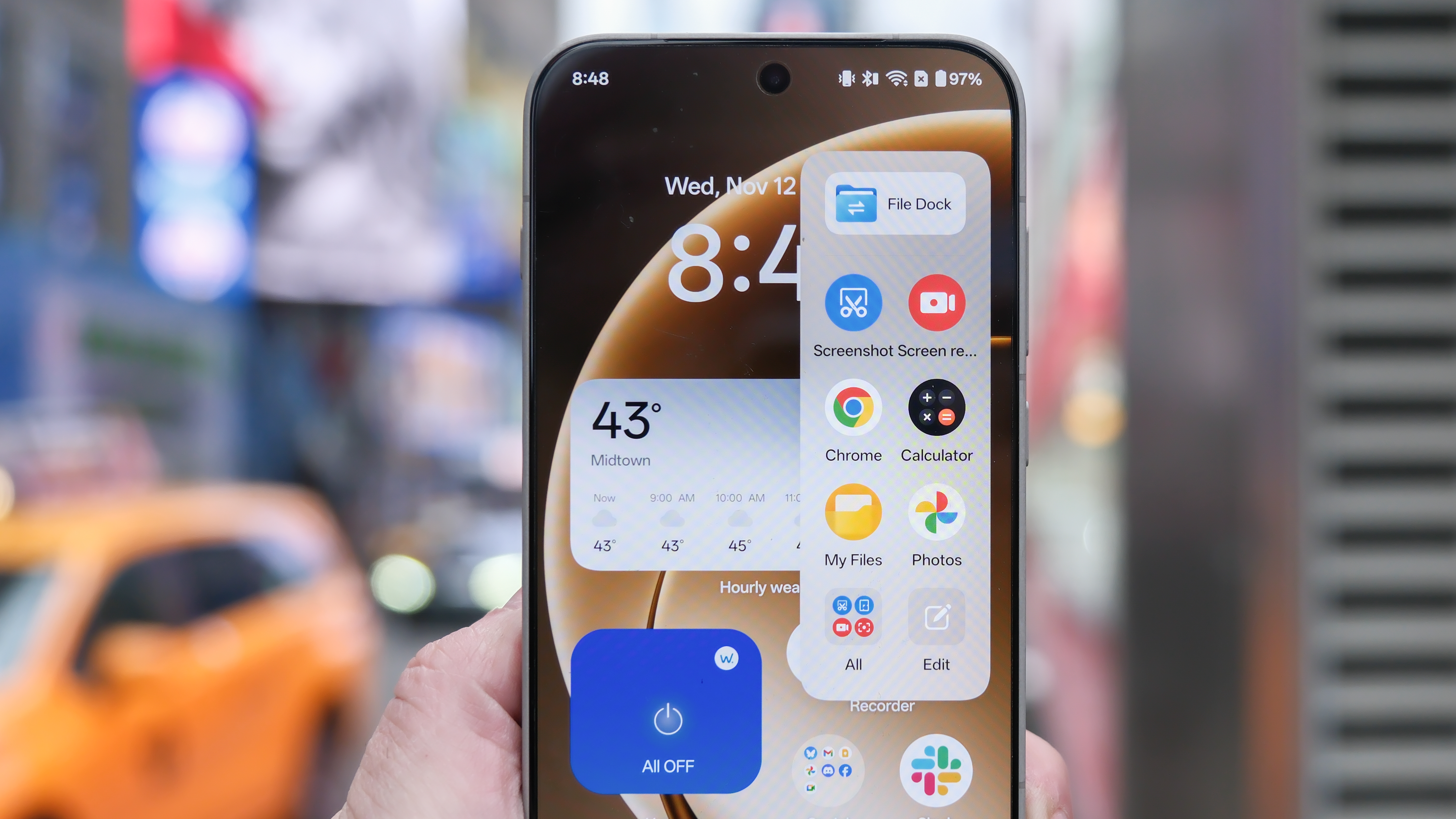 OnePlus 15 in Times Square New York City on the busy street showing the cameras and sides of the phone in addition to home screen panels and Settings menus