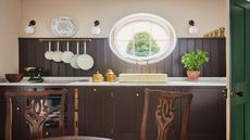 utility area with dark brown cabinets and oval shaped window