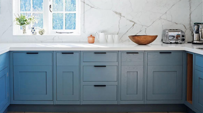 A blue kitchen with a marble backsplash