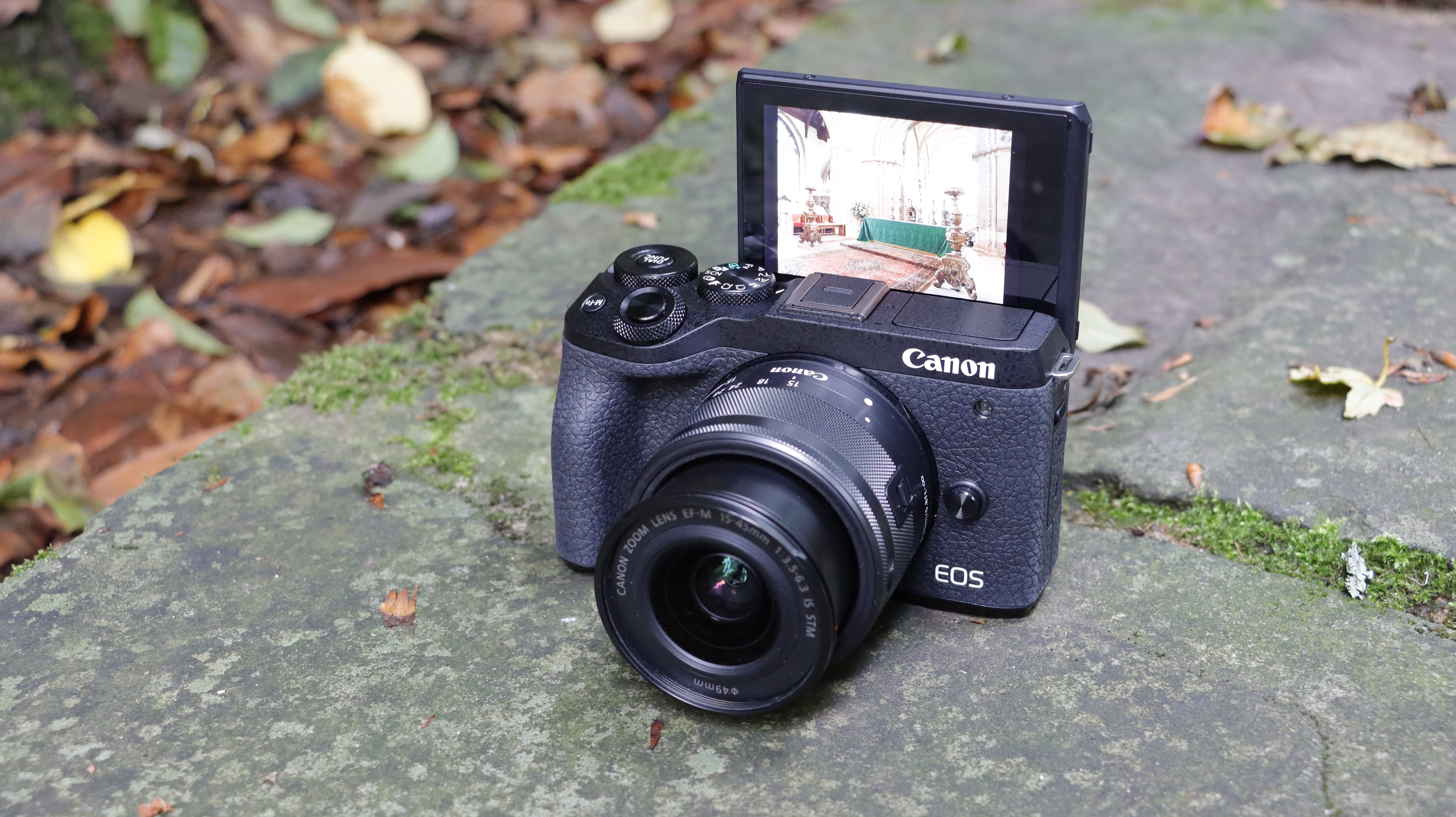 The Canon EOS M6 Mark II sat on a pathway with its articulating screen flipped up and facing forward