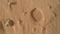 A close-up of the Martian surface with a wide, shallow pit. 