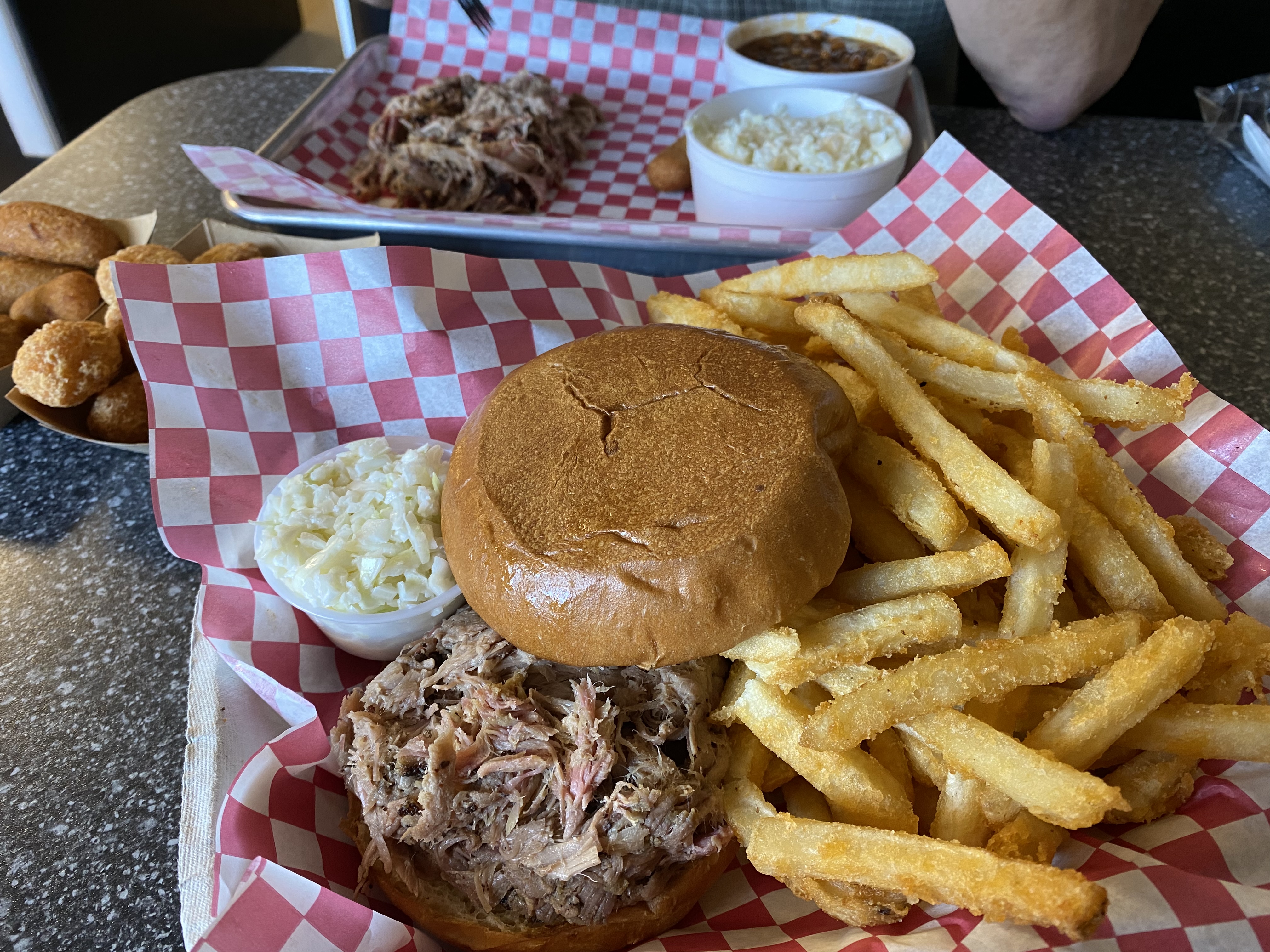 A plate with a barbecue pork sandwich and French fries