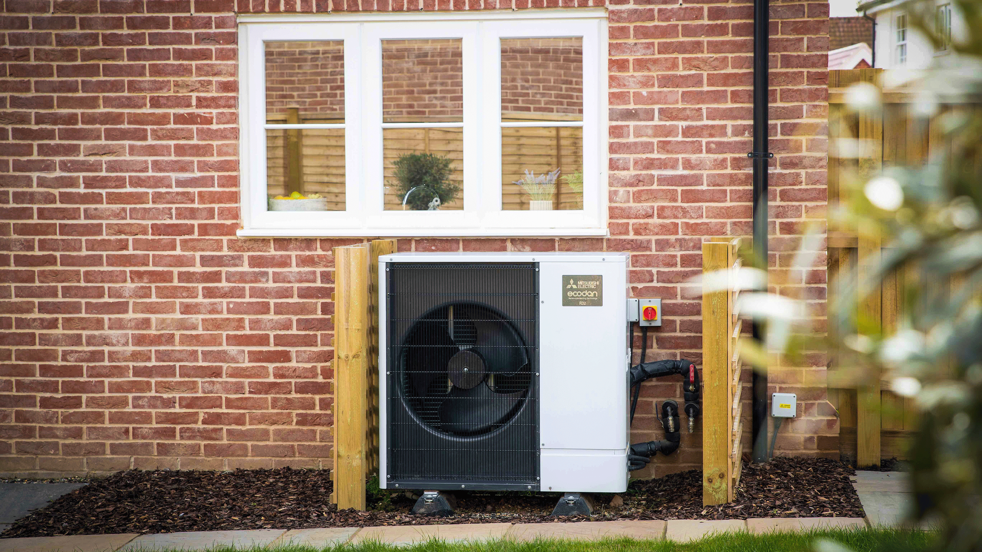 Heat pump outside black building with green lawn