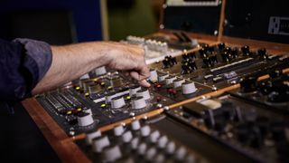 Engineer presses button on mastering console in a recording studio