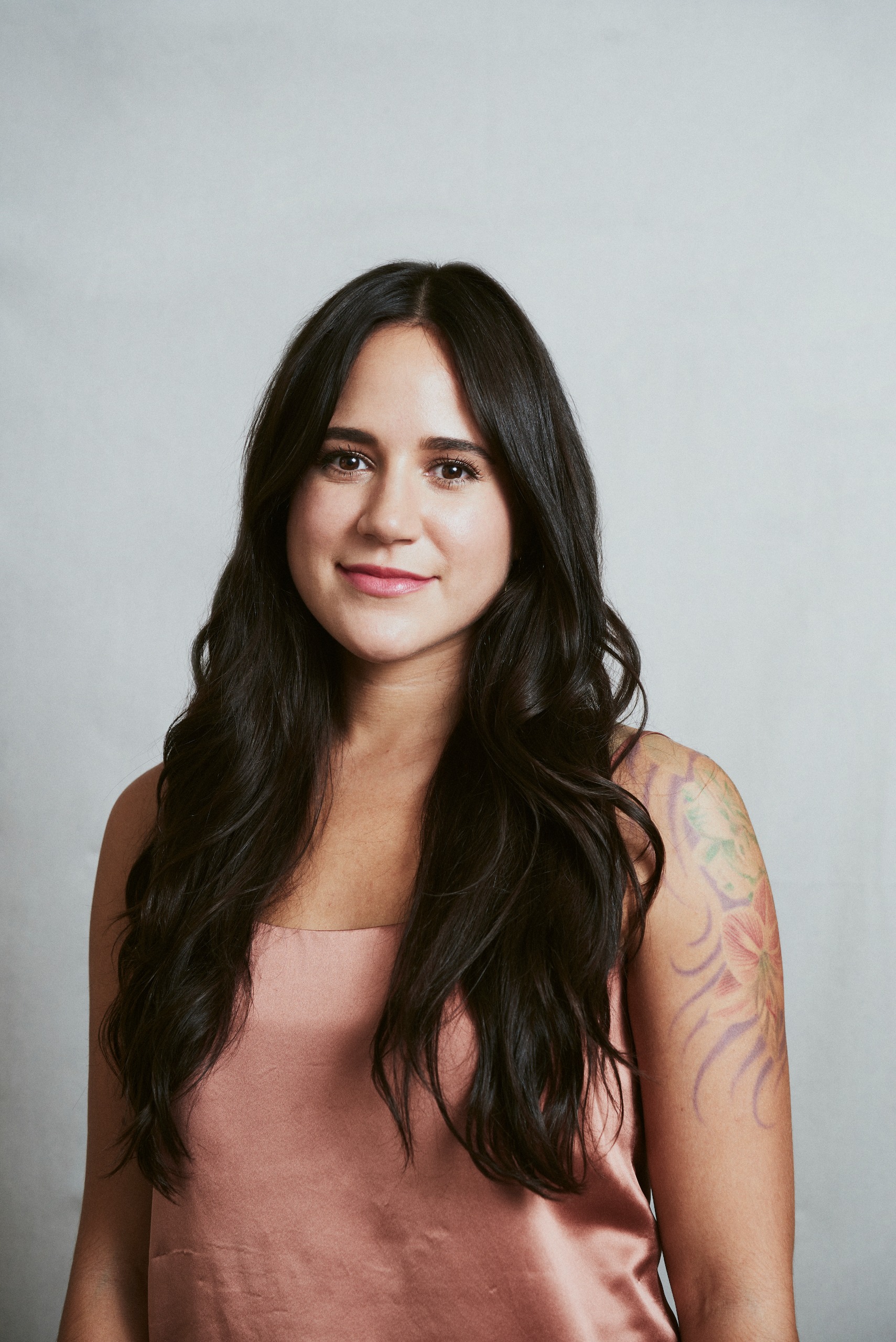 a white woman with dark brown hair in a pink tank top