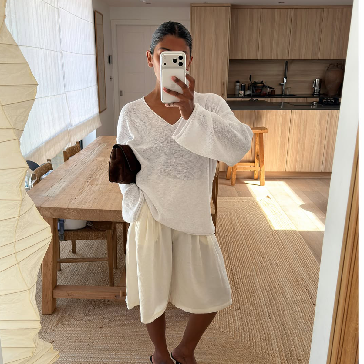 Monikh Dale wearing a white V-neck open-knit sweater