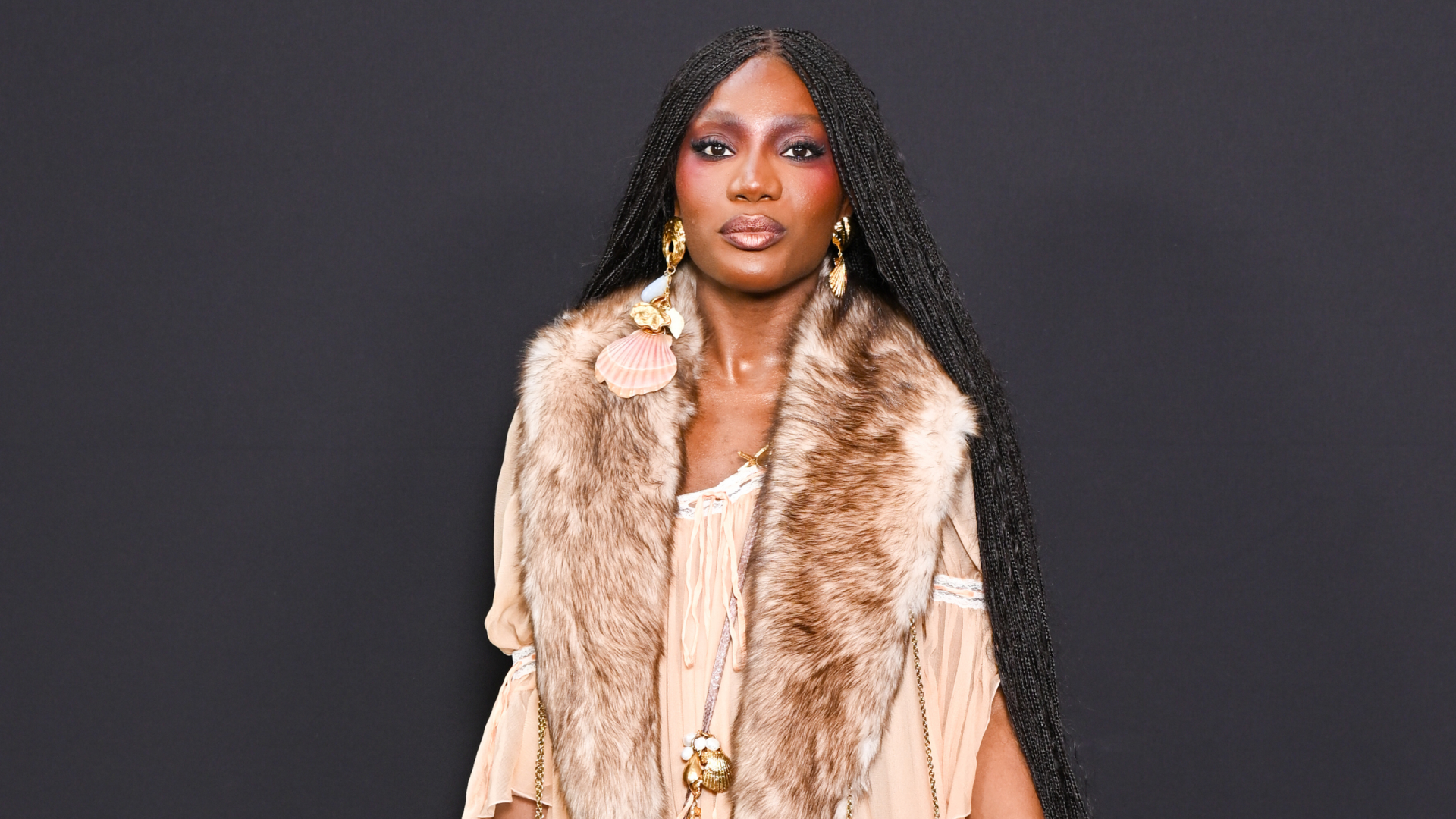 Doechii wearing braids and a bright blush color posing in front of the camera
