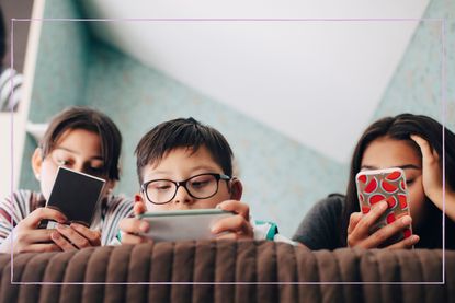 Children laying on the sofa on their phones