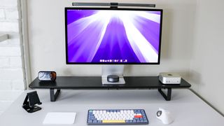 A desk setup built around the Mac mini M4 with a Studio Display, mechanical keyboard, trackball mouse and other accessories