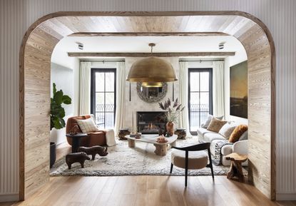 A living room with an arch, designed with all natural elements