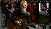 Glen Hansard watches performance of Freddie Mercury impersonator Brian Keville, during the annual Christmas Eve busk in aid of the Dublin Simon Community outside the Gaiety Theater in Dublin. 