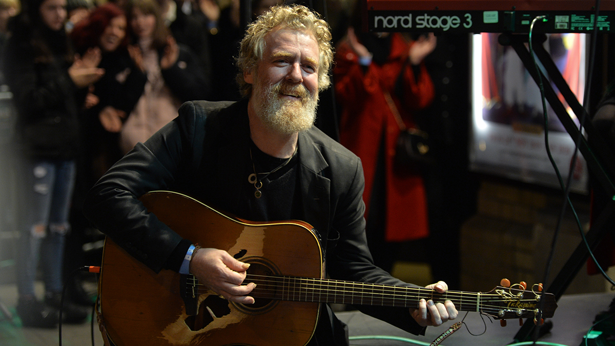 Glen Hansard watches performance of Freddie Mercury impersonator Brian Keville, during the annual Christmas Eve busk in aid of the Dublin Simon Community outside the Gaiety Theater in Dublin. 