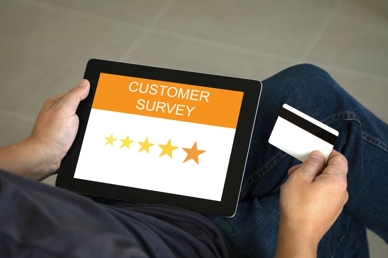 Man holding a tablet showing five stars ard reading &quot;customer survey&quot;