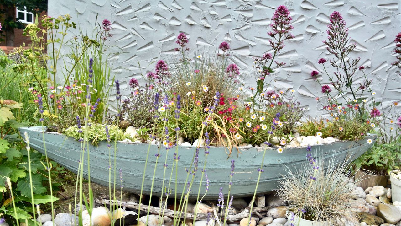 Blue wooden boat planter filled with wildflowers