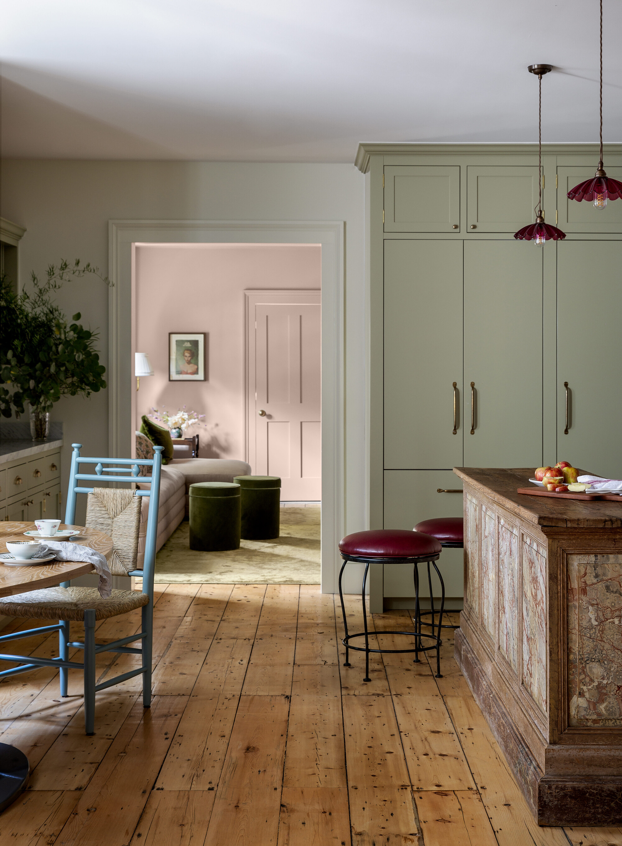 A kitchen with wooden flooring and sage green floor-to-ceiling kitchen cabinets