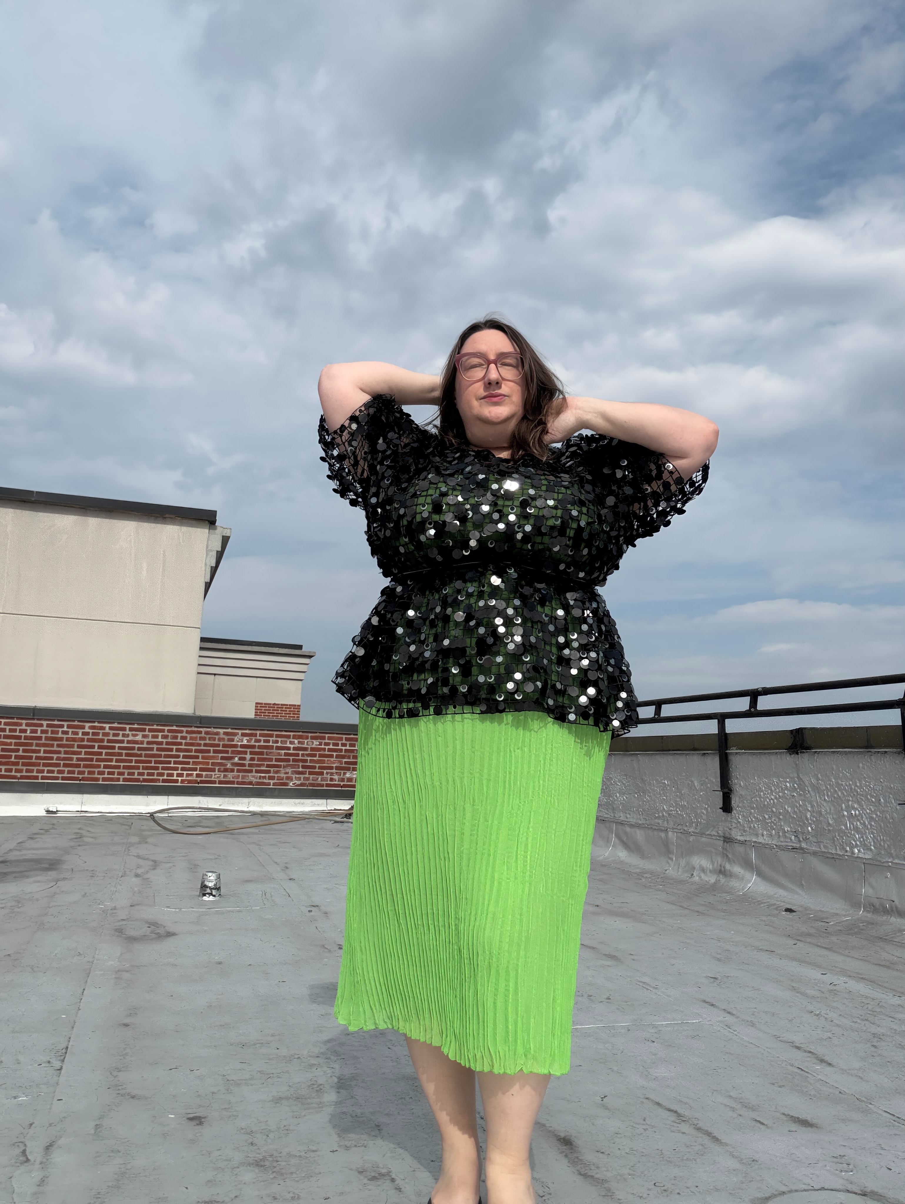 Sarah Chiwaya poses in a paillette-embellished peplum top layered over a lime green pleated skirt